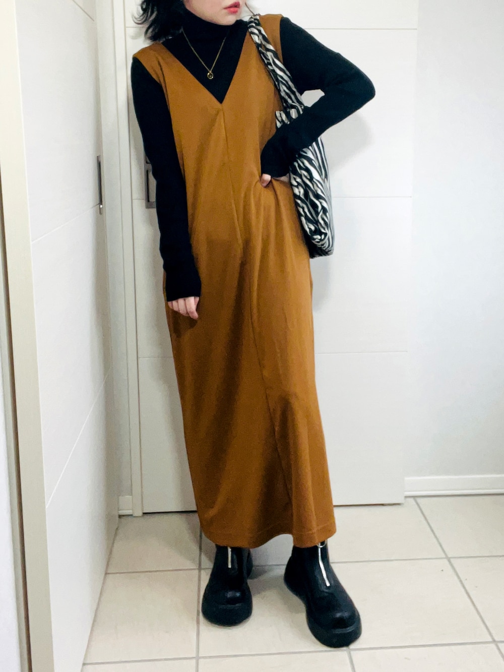 ブラウン系のサロペット/オーバーオール、ブラック系のニット/セーター、ブラック系のブーツを着用したレディースの秋コーディネートの2枚目の写真