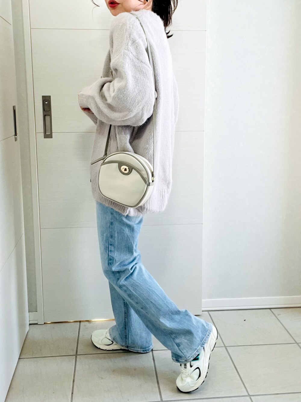 ホワイト系のTシャツ/カットソー、グレー系のカーディガン/ボレロ、ブルー系のデニムパンツを着用したレディースの冬コーディネートの5枚目の写真