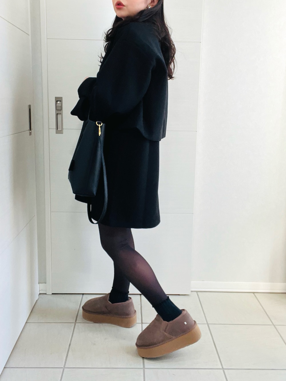 ブラック系のブルゾン、グレー系のTシャツ/カットソー、ブラック系のジャンパースカートを着用したレディースの冬コーディネートの3枚目の写真