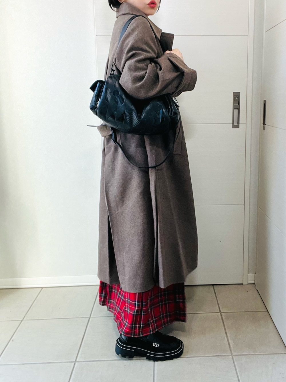 ブラウン系のステンカラーコート、ブラック系のスウェット、レッド系のスカートを着用したレディースの秋コーディネートの5枚目の写真