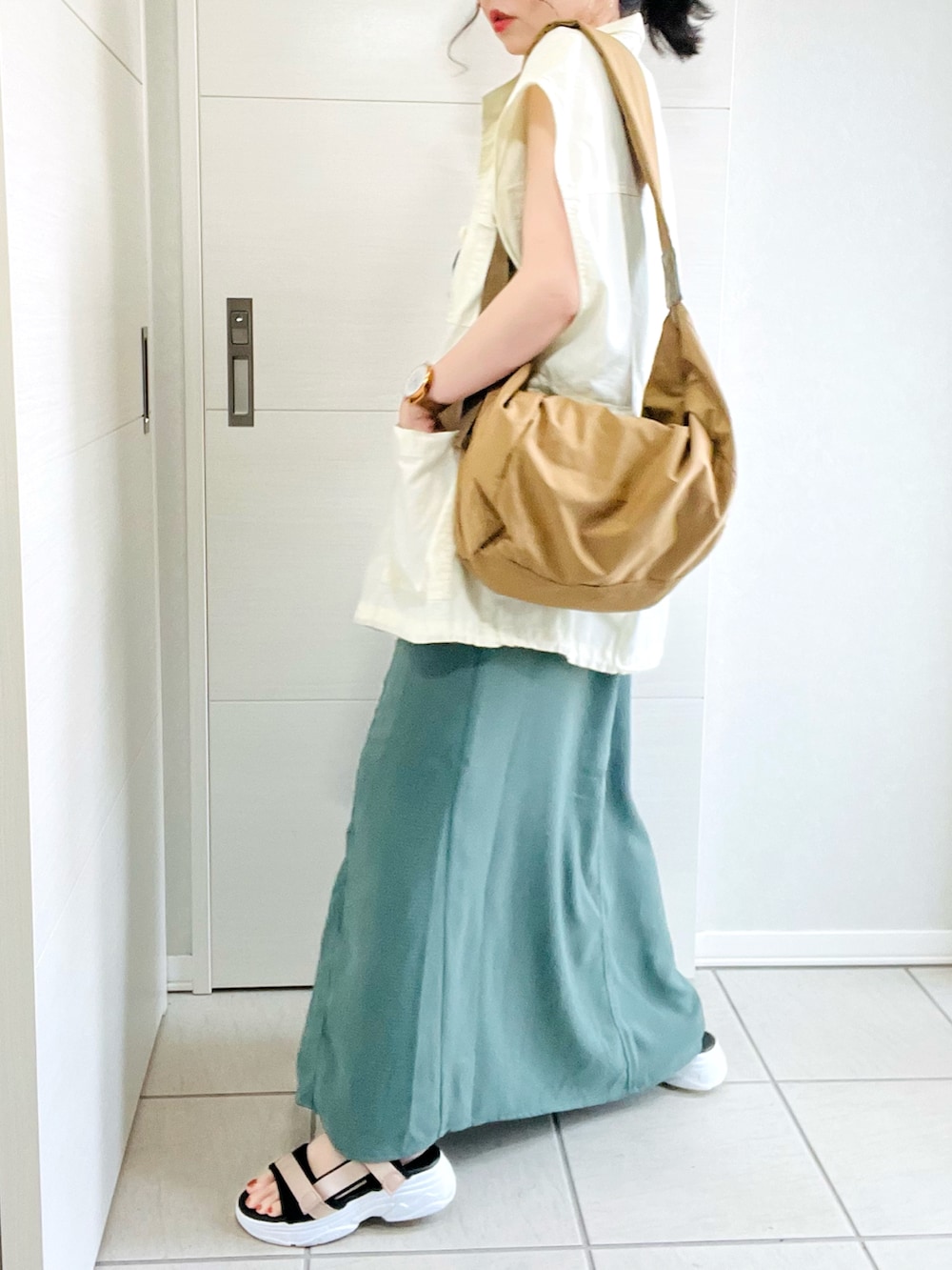 グリーン系のワンピース、ホワイト系のベスト、ベージュ系のサンダルを着用したレディースの夏コーディネートの3枚目の写真