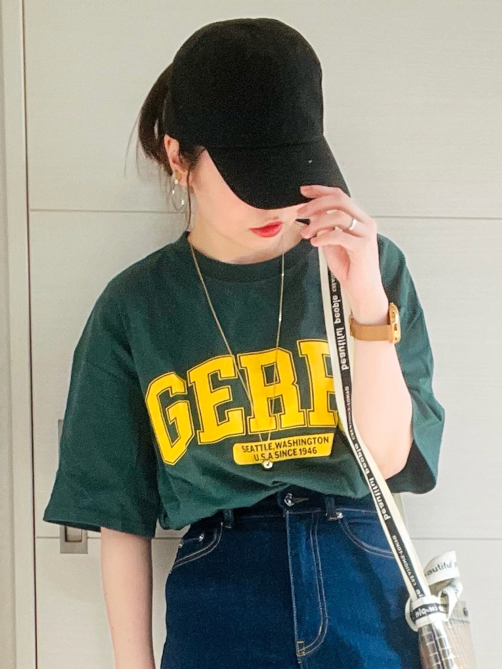 グリーン系のTシャツ/カットソー、ブルー系のデニムパンツ、ホワイト系のスニーカーを着用したレディースの夏コーディネートの2枚目の写真