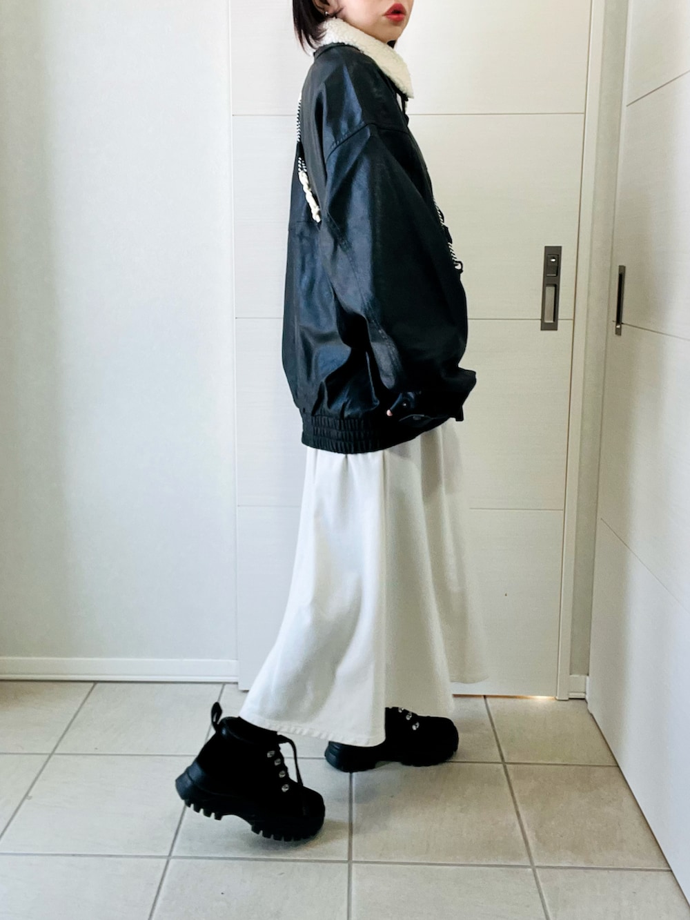 ブラック系のブルゾン、ホワイト系のワンピース、ブラック系のブーツを着用したレディースの冬コーディネートの4枚目の写真