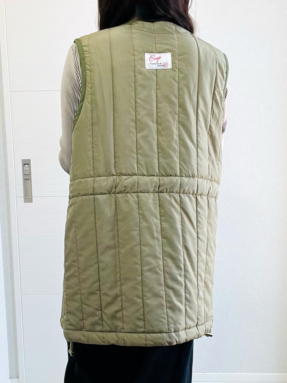 グリーン系のベスト、ベージュ系のTシャツ/カットソー、ブラック系のスカートを着用したレディースの秋コーディネートの3枚目の写真