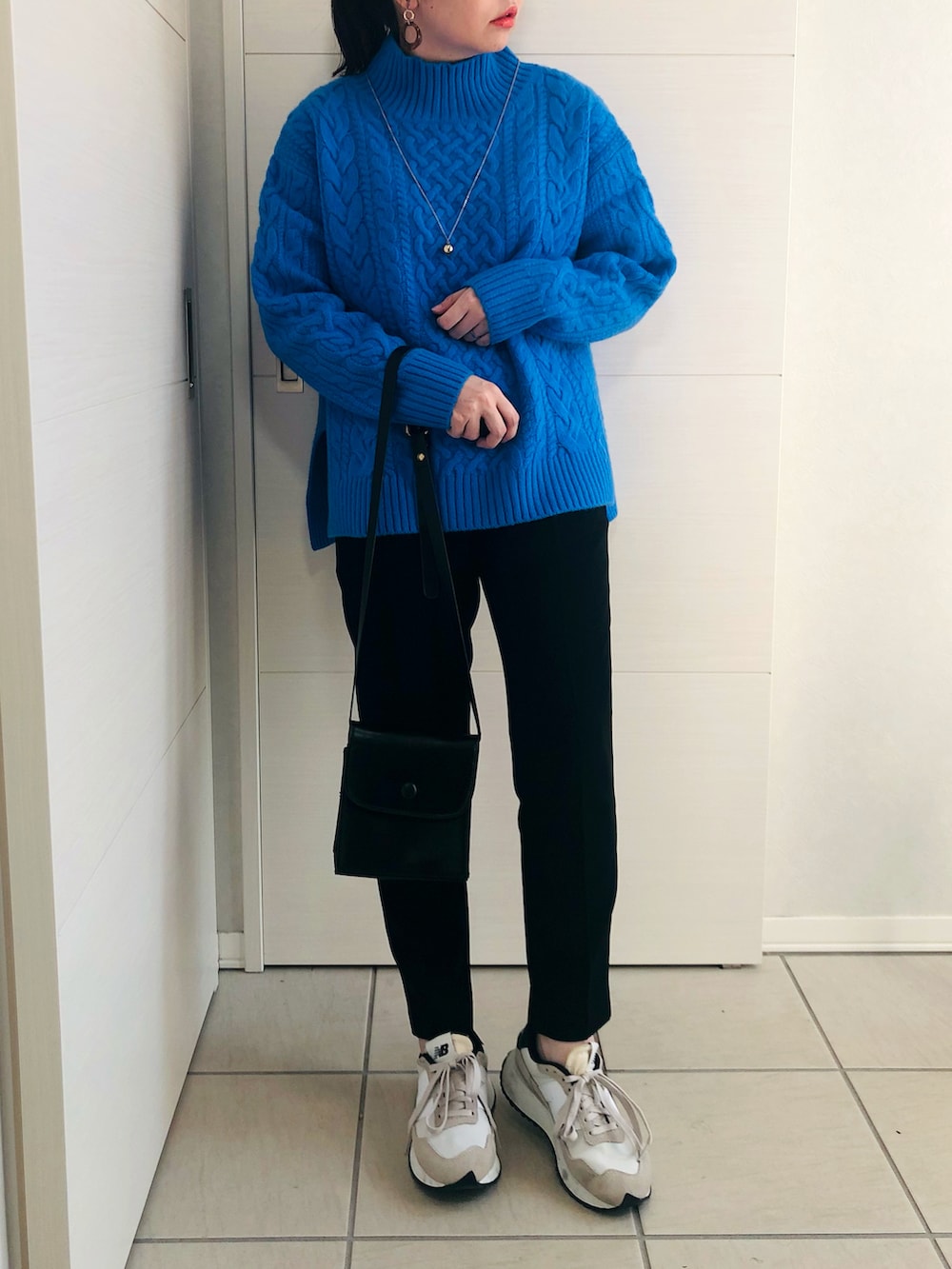 ブルー系のニット/セーター、ブラック系のパンツ、ホワイト系のスニーカーを着用したレディースの秋コーディネートの2枚目の写真