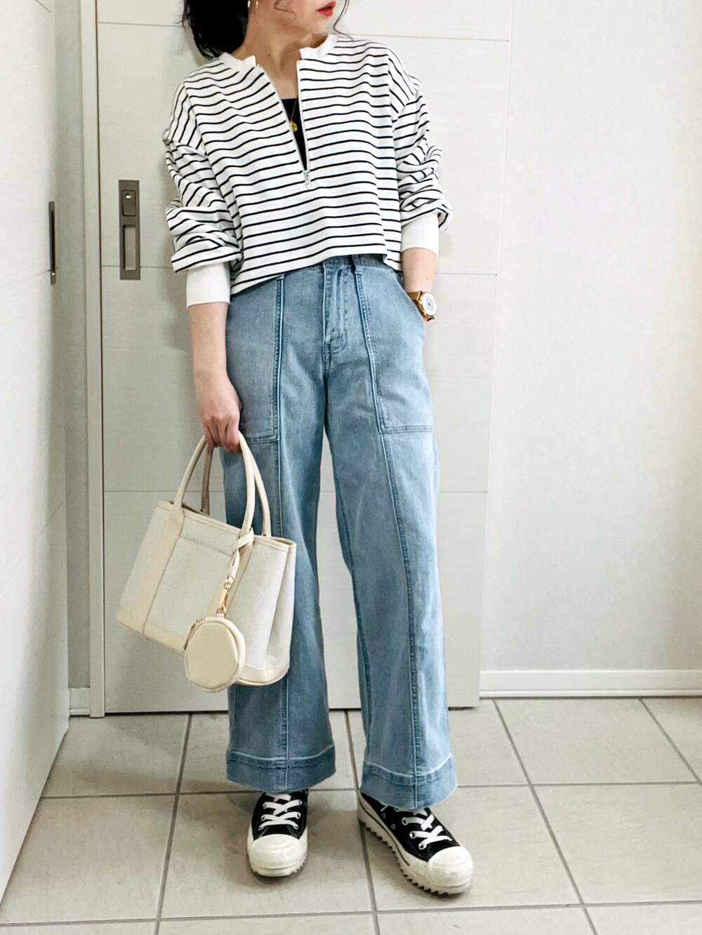 ブラック系のワンピース、ブルー系のデニムパンツ、ブラック系のスニーカーを着用したレディースの春コーディネートの2枚目の写真