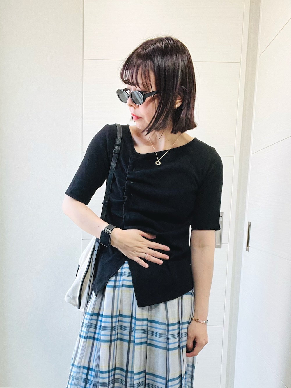 ブラック系のTシャツ/カットソー、ホワイト系のスカート、ブラック系のスニーカーを着用したレディースの秋コーディネートの2枚目の写真