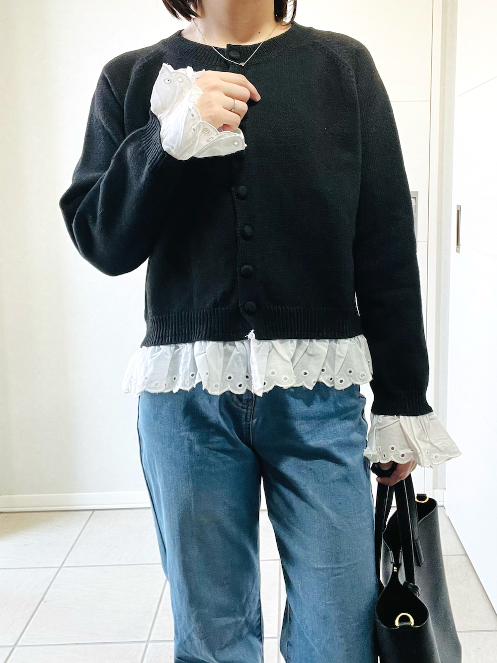 グレー系のスニーカー、ブルー系のデニムパンツ、ブラック系のカーディガン/ボレロを着用したレディースの春コーディネートの2枚目の写真