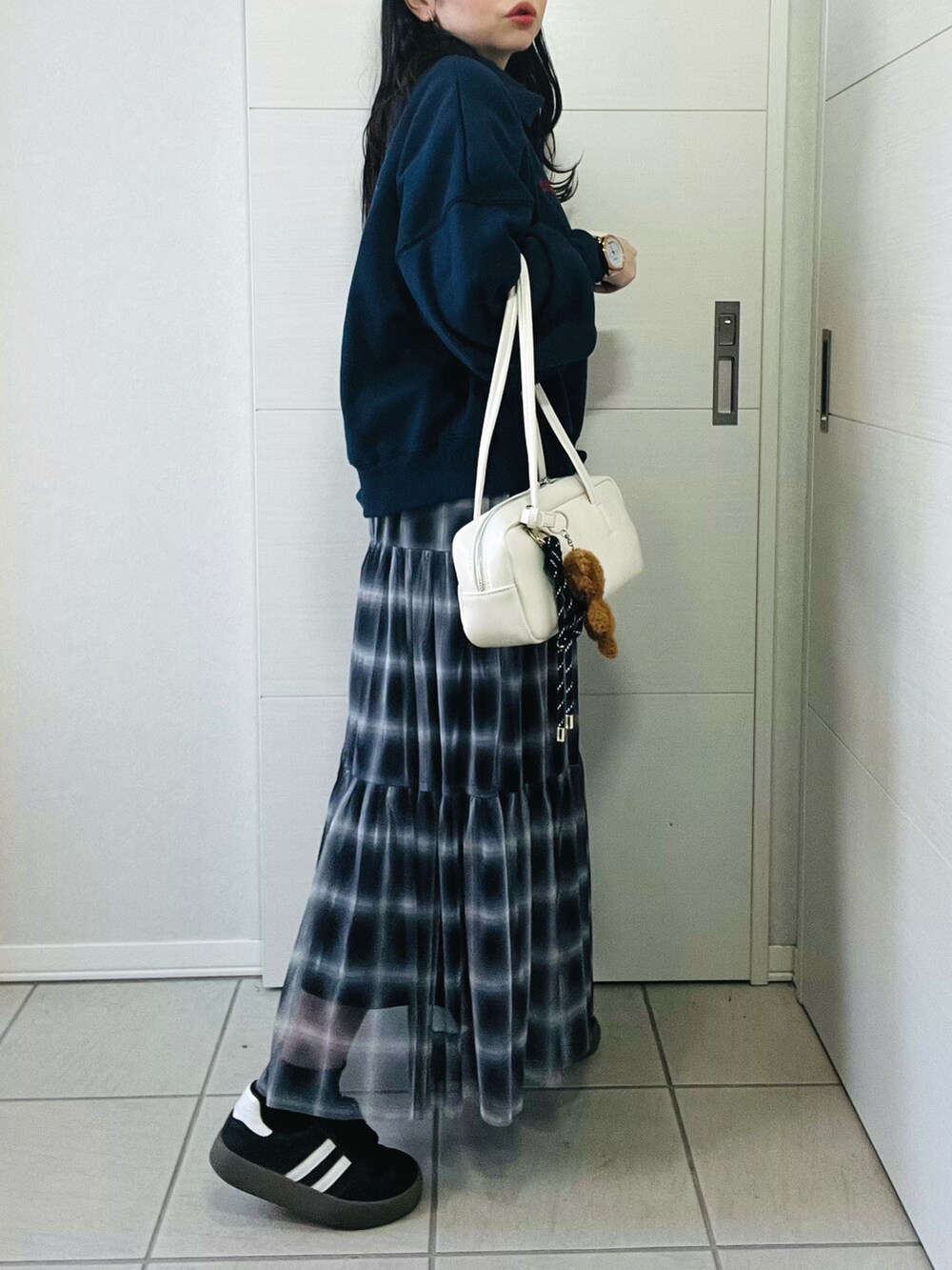 ブラック系のスカート、ブルー系のスウェット、ホワイト系のボストンバッグを着用したレディースの秋コーディネートの4枚目の写真