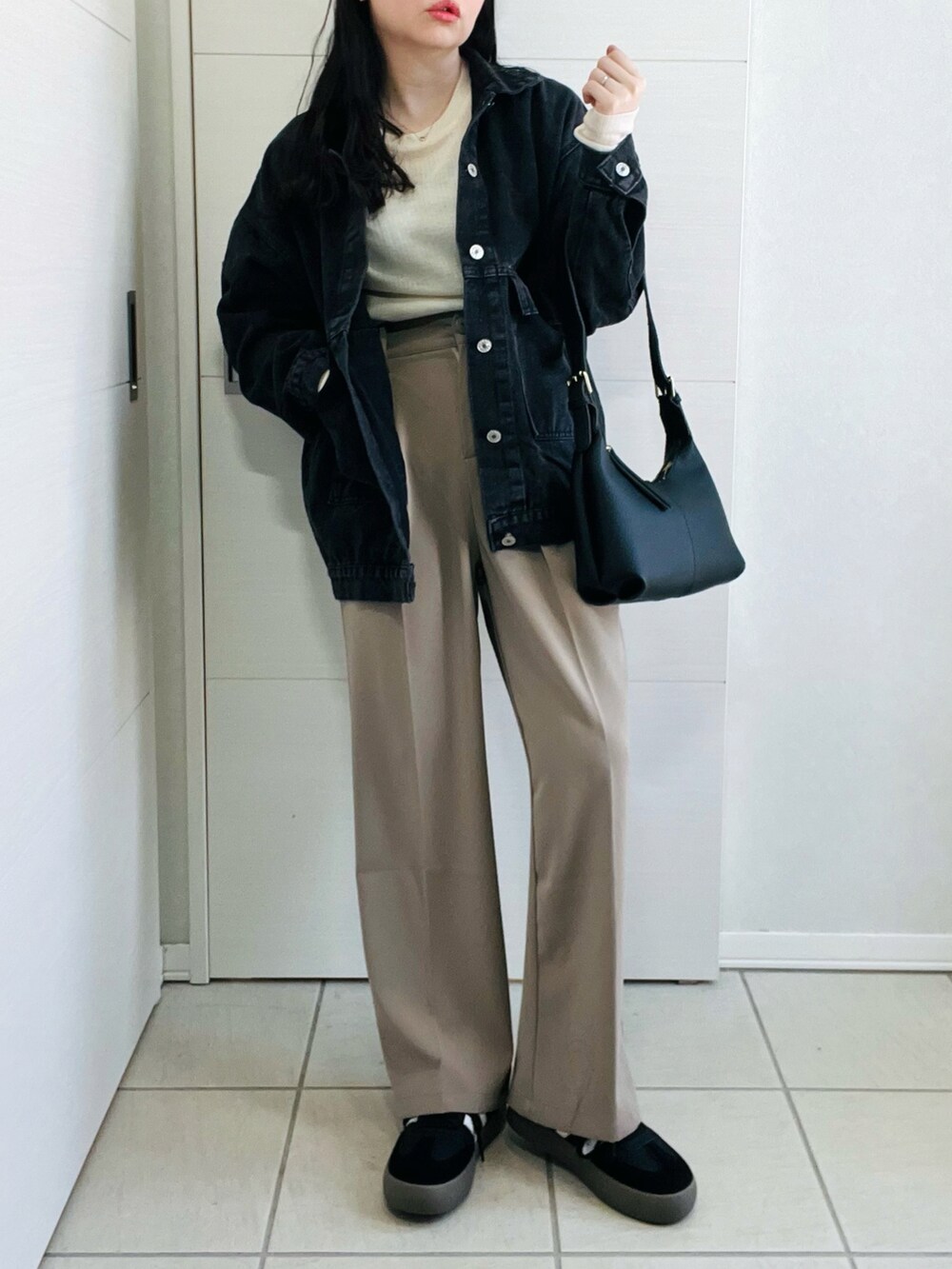 ブラック系のデニムジャケット、ブラック系のスニーカー、ブラック系のショルダーバッグを着用したレディースの冬コーディネートの2枚目の写真