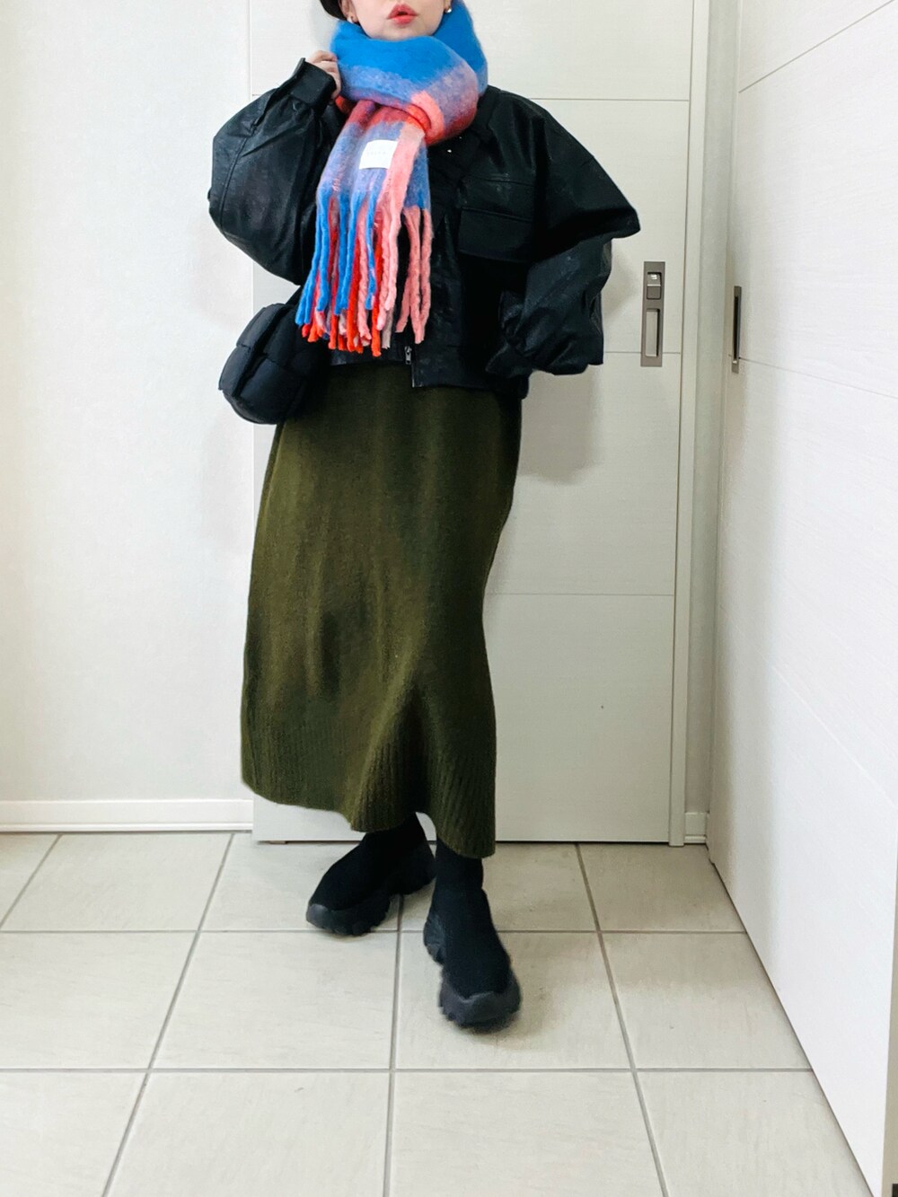 ブラック系のブルゾン、グリーン系のワンピース、ブラック系のブーツを着用したレディースの冬コーディネートの2枚目の写真