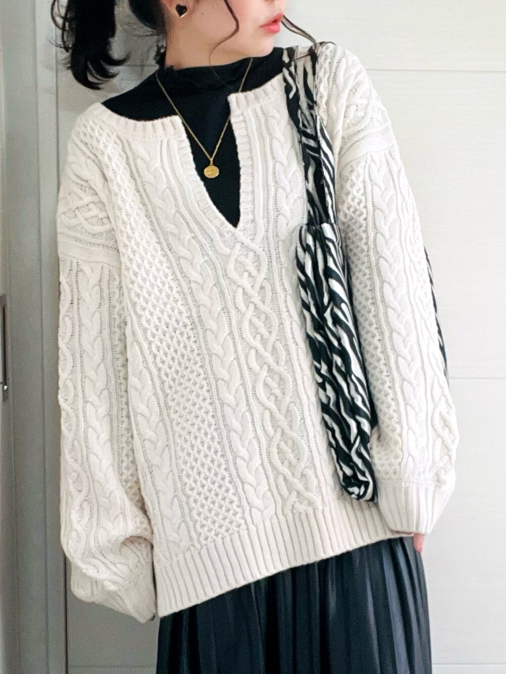 ホワイト系のニット/セーター、ブラック系のTシャツ/カットソー、ブラック系のスカートを着用したレディースの秋コーディネートの2枚目の写真