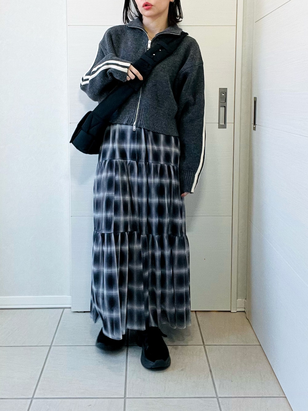 グレー系のニット/セーター、ブラック系のスカート、ブラック系のスニーカーを着用したレディースの冬コーディネートの3枚目の写真