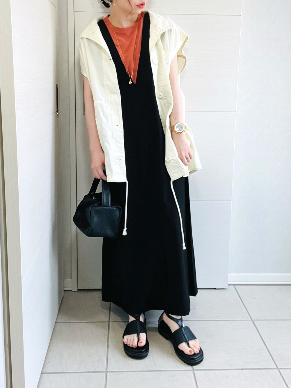 ホワイト系のベスト、オレンジ系のTシャツ/カットソー、ブラック系のワンピースを着用したレディースの夏コーディネートの3枚目の写真