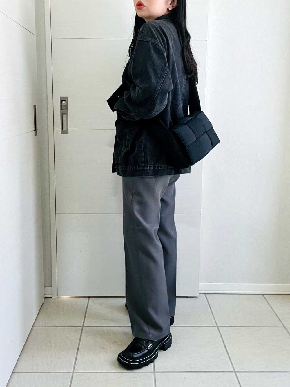 ブラック系のデニムジャケット、グレー系のスラックス、ブラック系のローファーを着用したレディースの春コーディネートの5枚目の写真