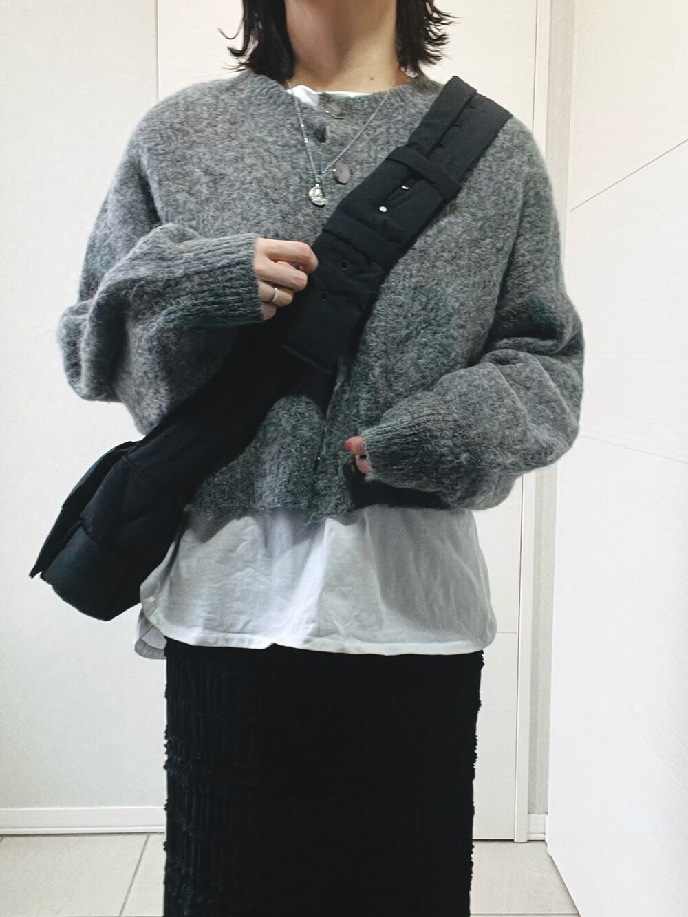 グレー系のカーディガン/ボレロ、ホワイト系のTシャツ/カットソー、ブラック系のスカートを着用したレディースの冬コーディネートの3枚目の写真