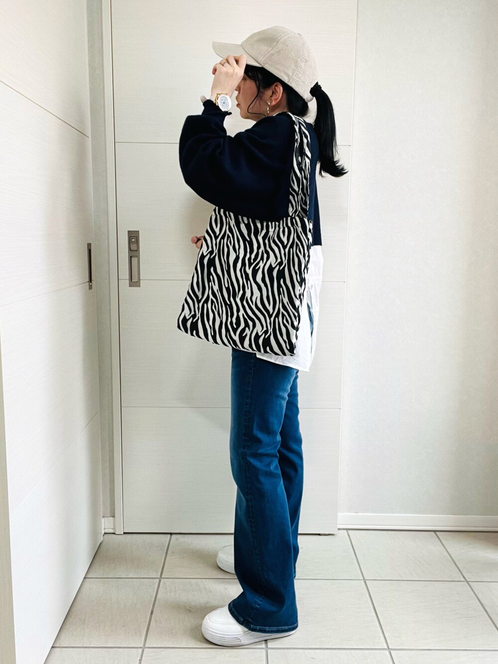 ブルー系のニット/セーター、ブルー系のデニムパンツ、ホワイト系のスニーカーを着用したレディースの春コーディネートの2枚目の写真