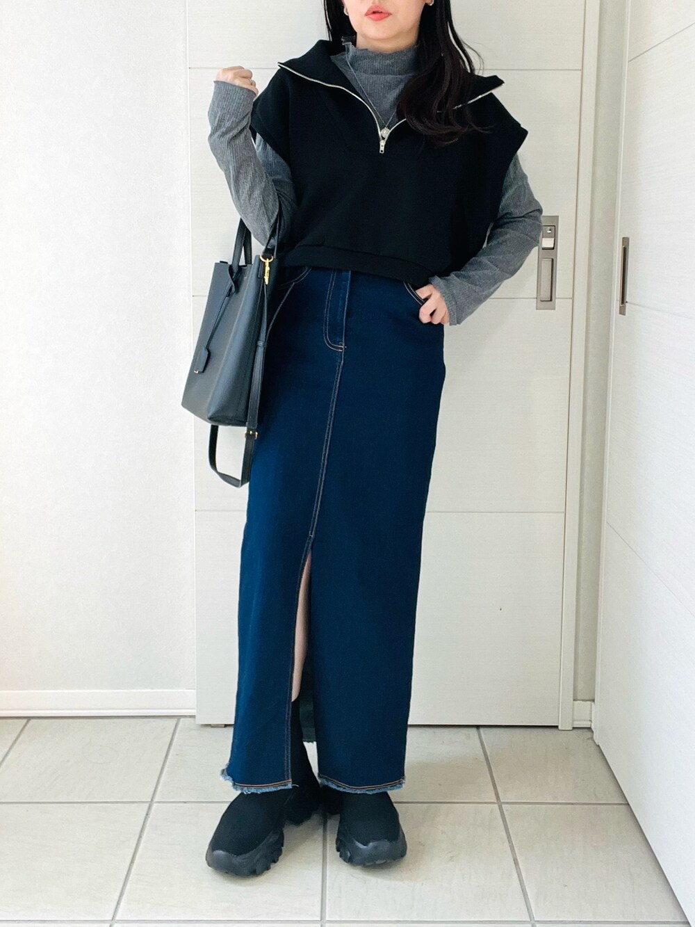ブラック系のベスト、グレー系のTシャツ/カットソー、ブルー系のデニムスカートを着用したレディースの秋コーディネートの4枚目の写真
