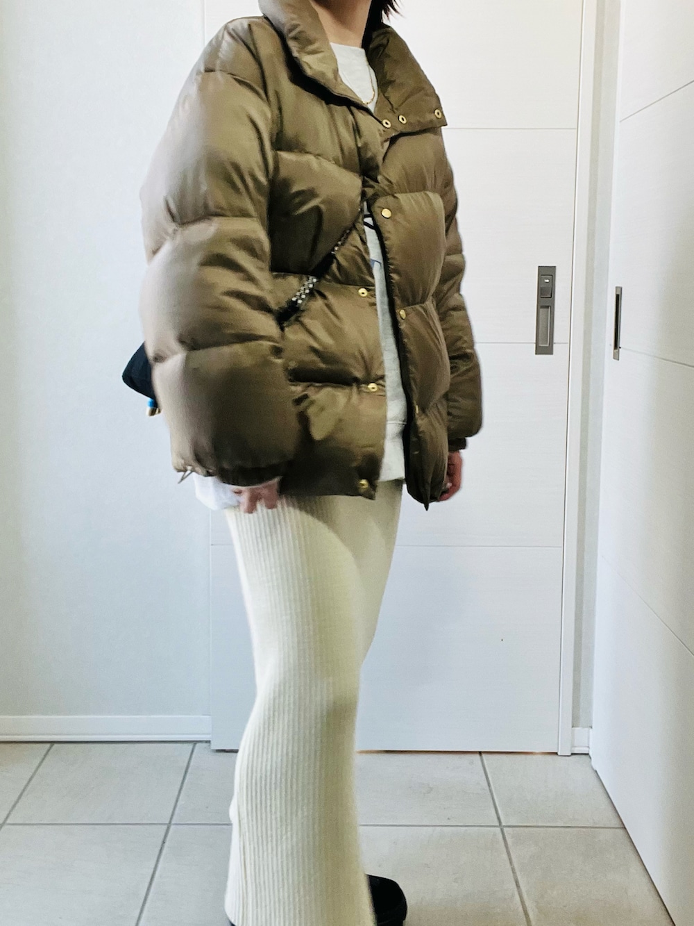 ベージュ系のダウンジャケット/コート、ホワイト系のスカート、ブラック系のブーツを着用したレディースの冬コーディネートの2枚目の写真