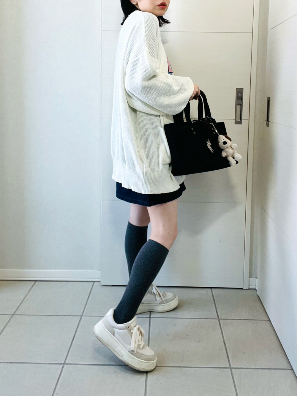 ホワイト系のカーディガン/ボレロ、グレー系のTシャツ/カットソー、ブルー系のデニムスカートを着用したレディースの春コーディネートの5枚目の写真