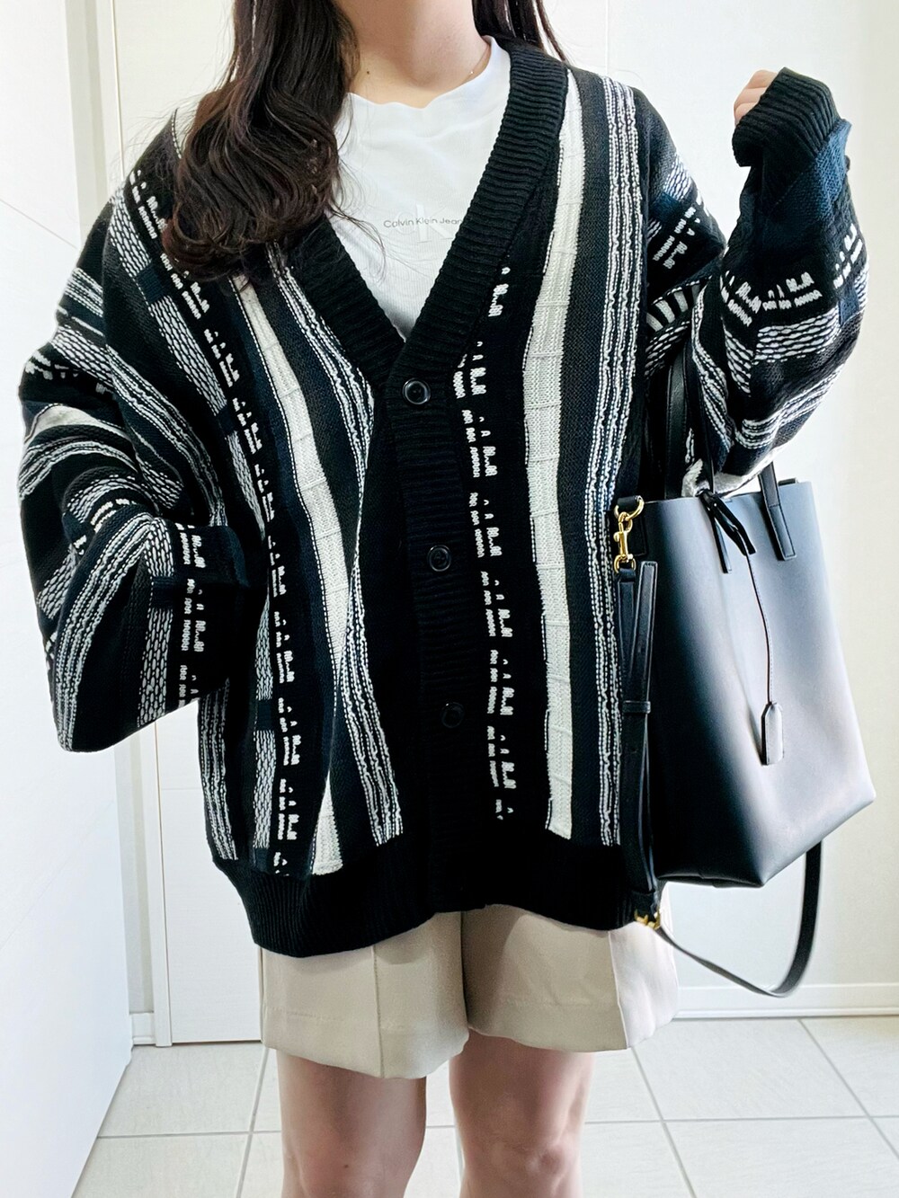 ブラック系のカーディガン/ボレロ、ホワイト系のスラックス、ブラック系のローファーを着用したレディースの春コーディネートの2枚目の写真