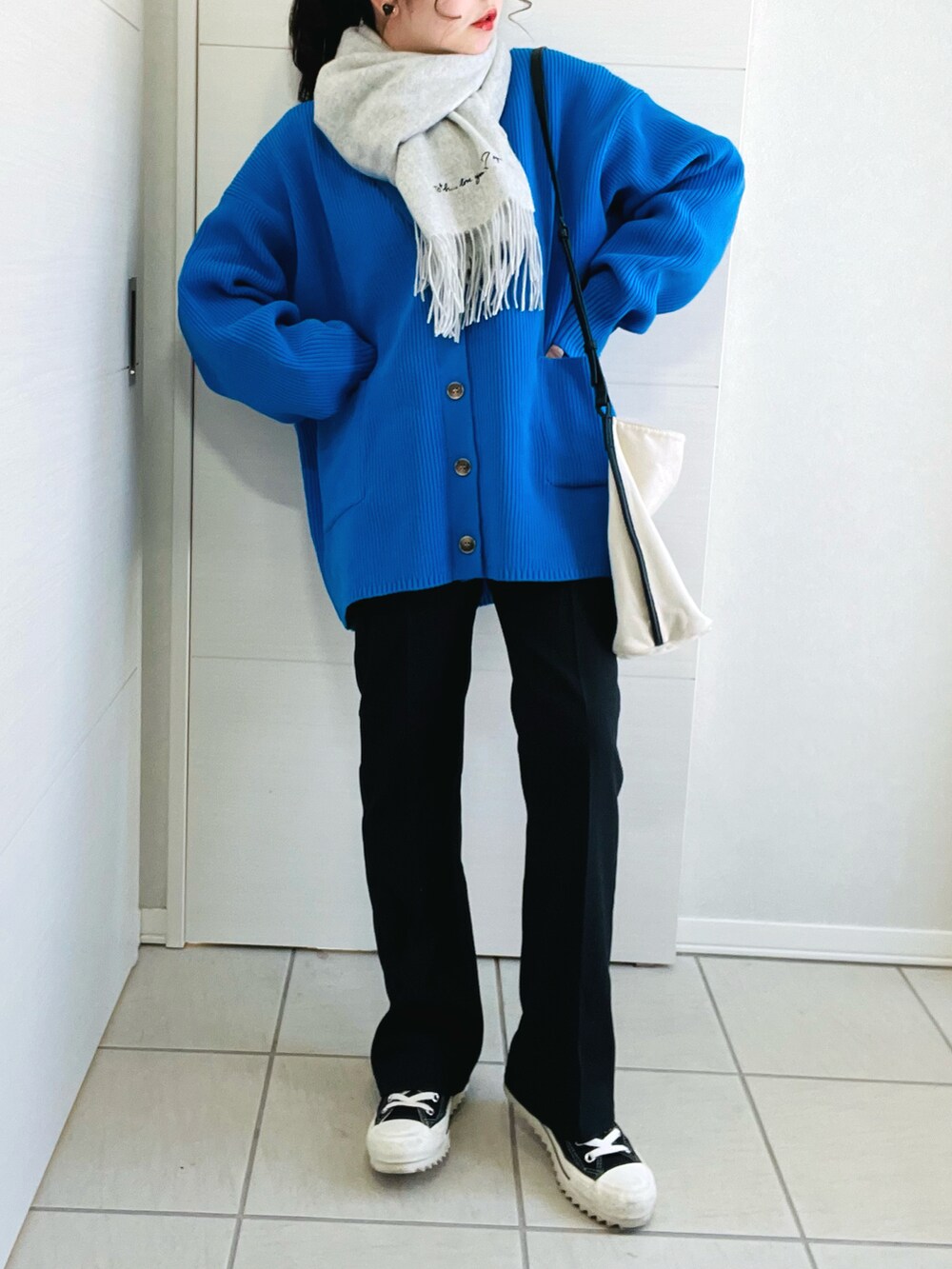 ブルー系のカーディガン/ボレロ、ホワイト系のTシャツ/カットソー、ブラック系のスラックスを着用したレディースの春コーディネートの3枚目の写真