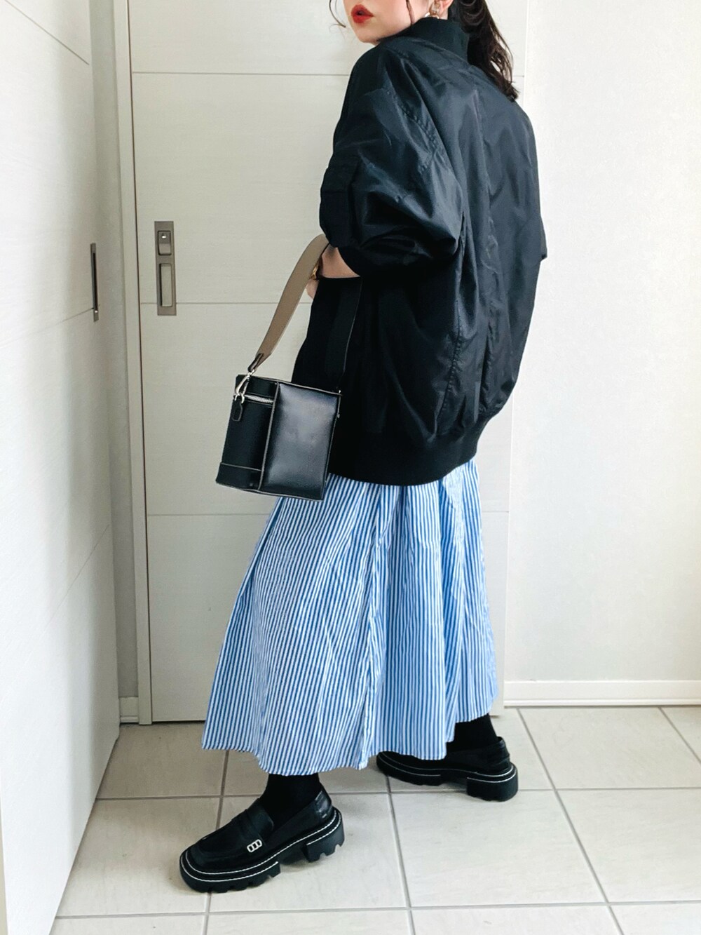 ブルー系のシャツワンピース、ブラック系のブルゾン、ブラック系のローファーを着用したレディースの春コーディネートの5枚目の写真