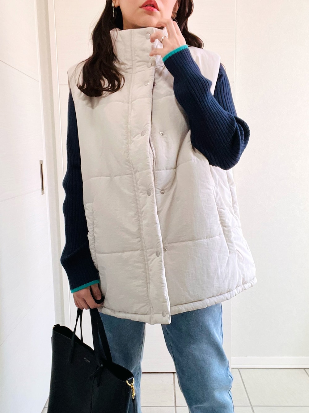 ホワイト系のベスト、ブルー系のデニムパンツ、ブルー系のニット/セーターを着用したレディースの秋コーディネートの2枚目の写真