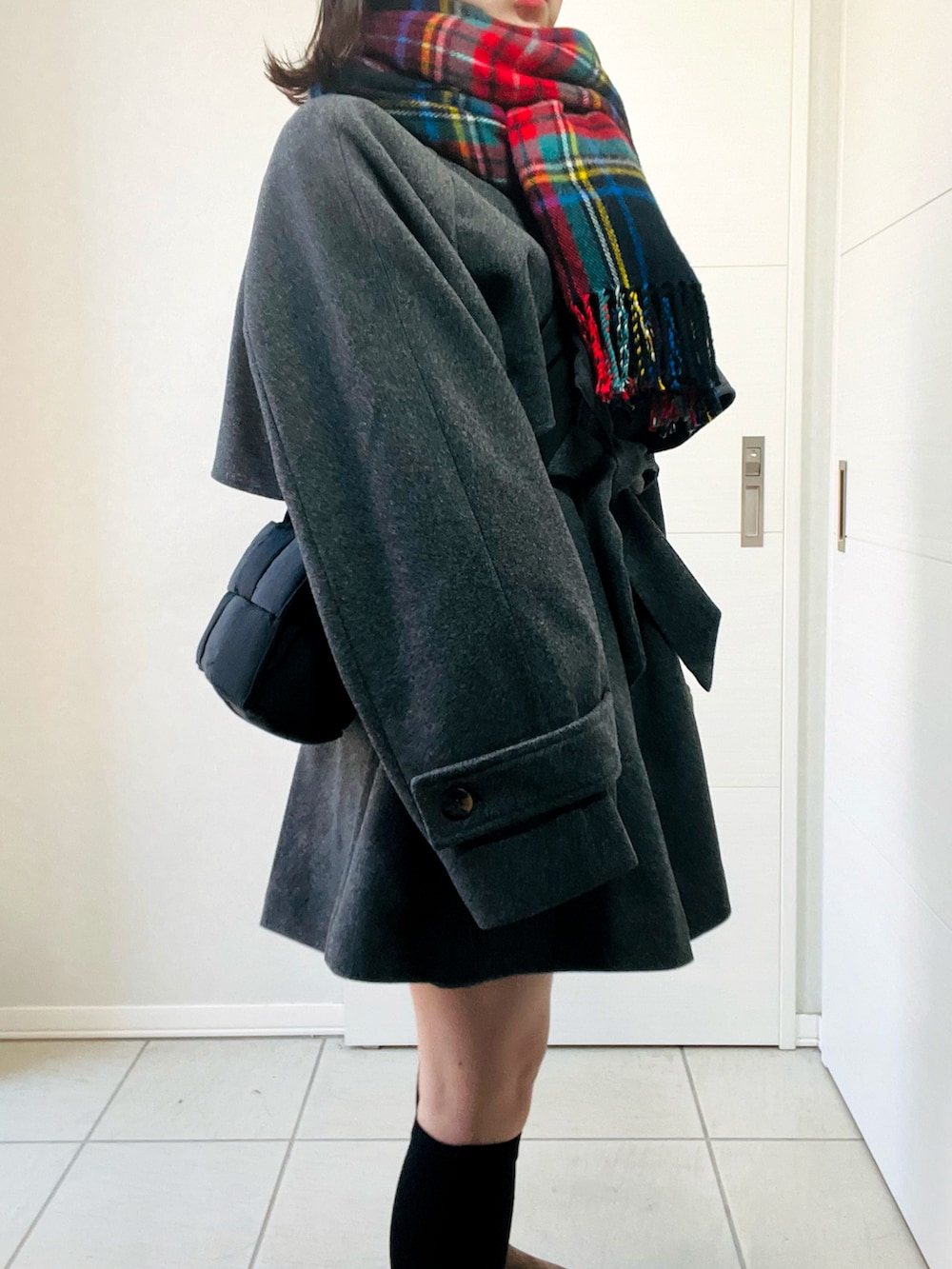 グレー系のトレンチコート、ベージュ系のスリッポン、ブラック系のショルダーバッグを着用したレディースの秋コーディネートの5枚目の写真