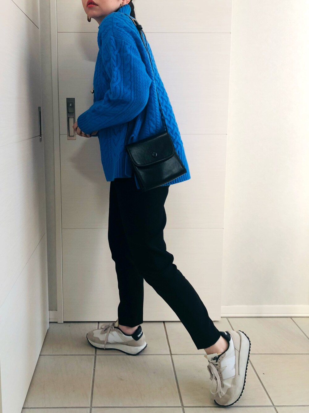 ブルー系のニット/セーター、ブラック系のパンツ、ホワイト系のスニーカーを着用したレディースの秋コーディネートの4枚目の写真