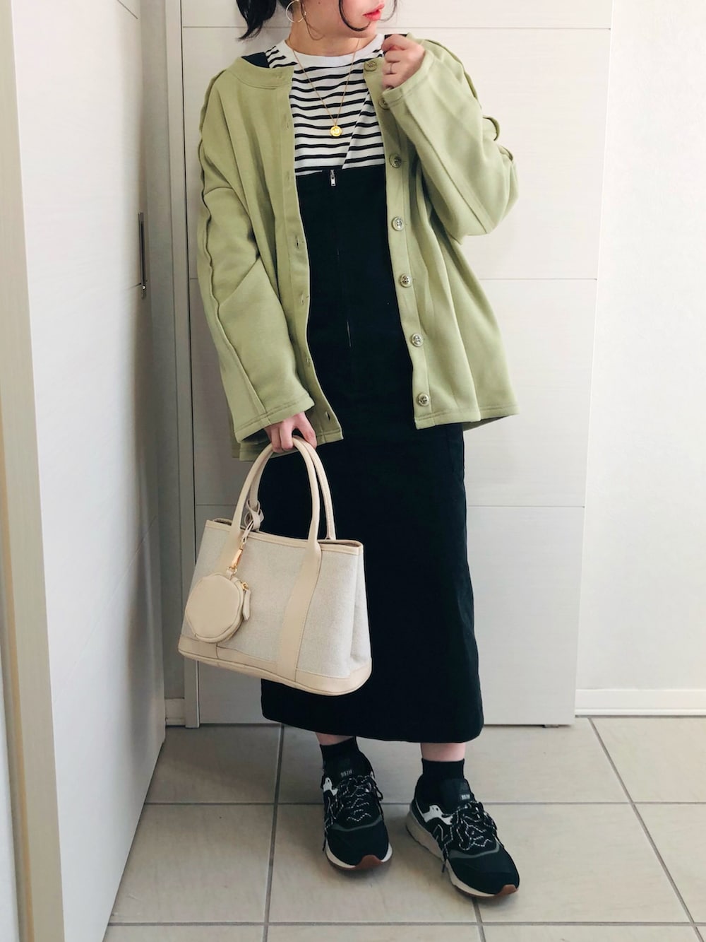 グリーン系のカーディガン/ボレロ、ブラック系のTシャツ/カットソー、ブラック系のジャンパースカートを着用したレディースの冬コーディネートの2枚目の写真