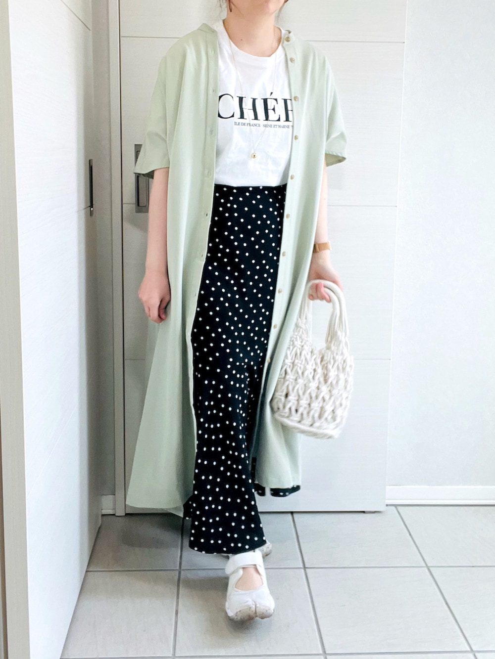 ホワイト系のTシャツ/カットソー、グリーン系のワンピース、ブラック系のスカートを着用したレディースの春コーディネートの3枚目の写真