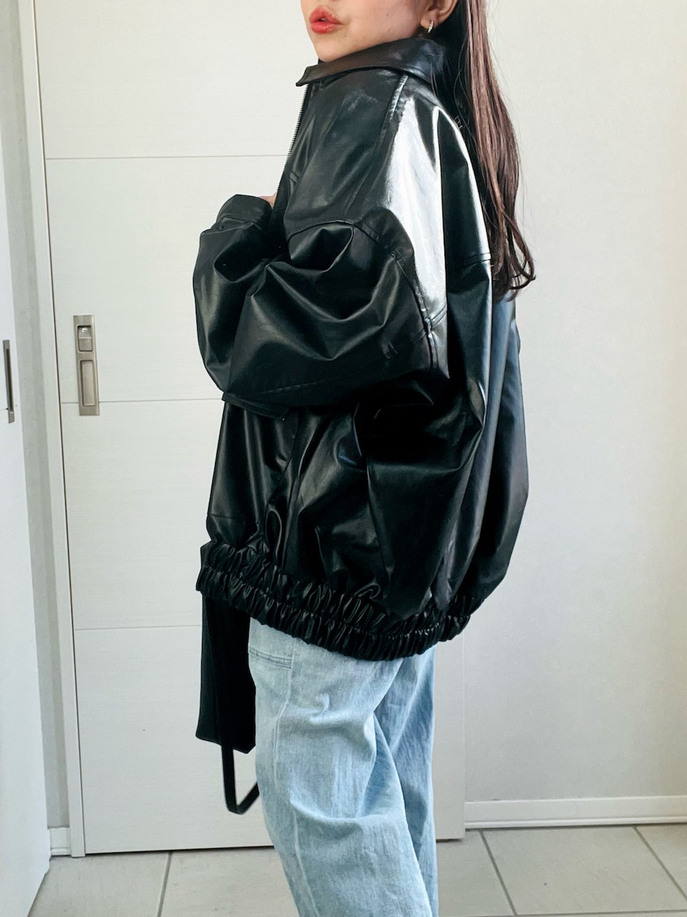 ブラック系のブルゾン、ホワイト系のTシャツ/カットソー、ブルー系のデニムパンツを着用したレディースの冬コーディネートの3枚目の写真