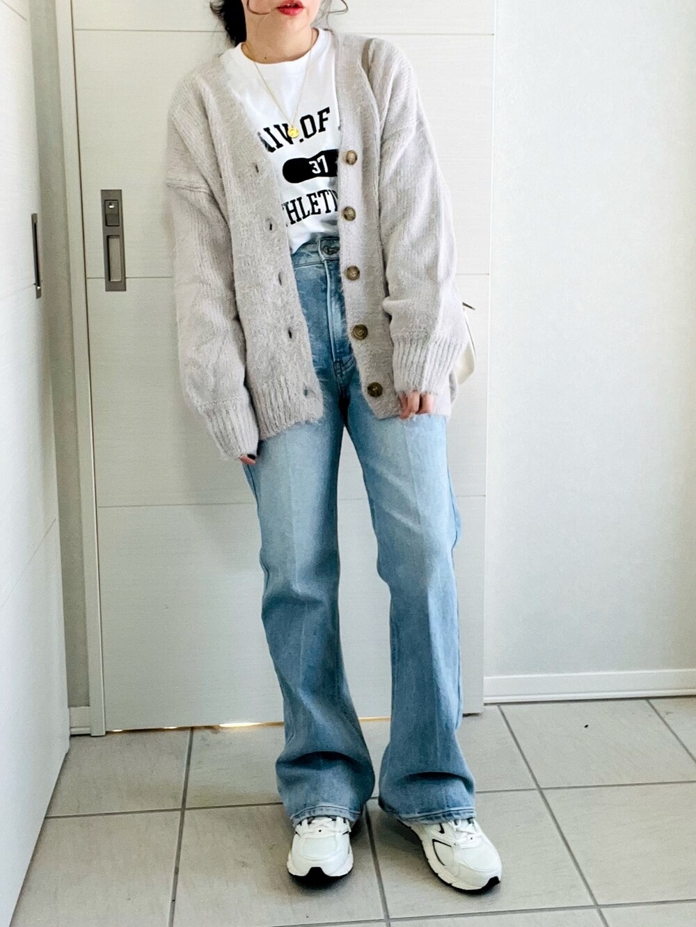 ホワイト系のTシャツ/カットソー、グレー系のカーディガン/ボレロ、ブルー系のデニムパンツを着用したレディースの冬コーディネートの2枚目の写真