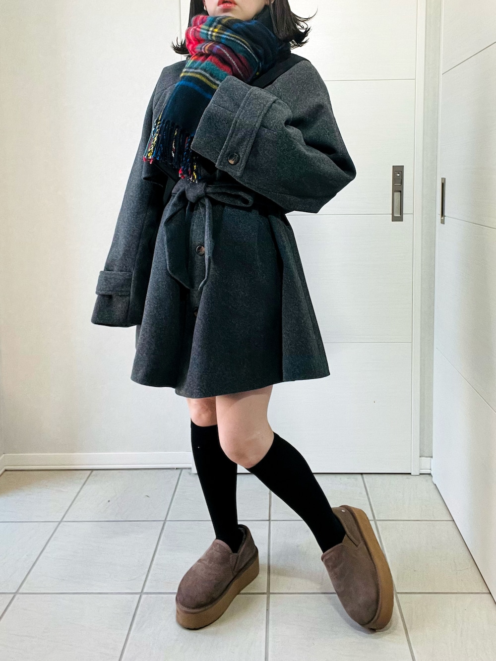 グレー系のトレンチコート、ベージュ系のスリッポン、ブラック系のショルダーバッグを着用したレディースの秋コーディネートの2枚目の写真