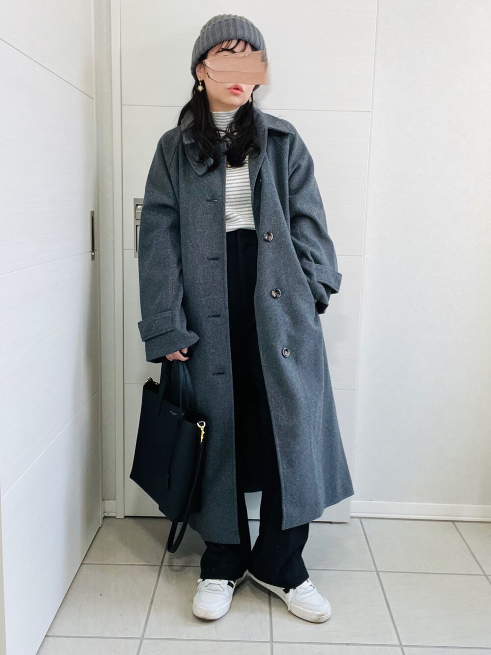 グレー系のステンカラーコート、グレー系のニット/セーター、ブラック系のスラックスを着用したレディースの冬コーディネートの5枚目の写真