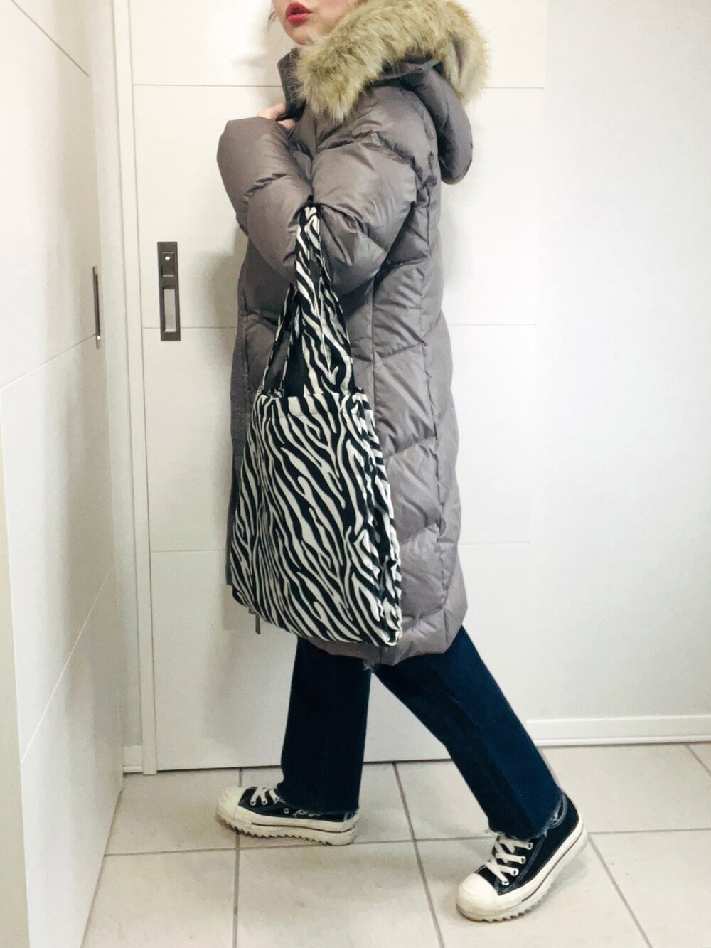 ブラウン系のダウンジャケット/コート、オレンジ系のニット/セーター、ブルー系のデニムパンツを着用したレディースの秋コーディネートの4枚目の写真