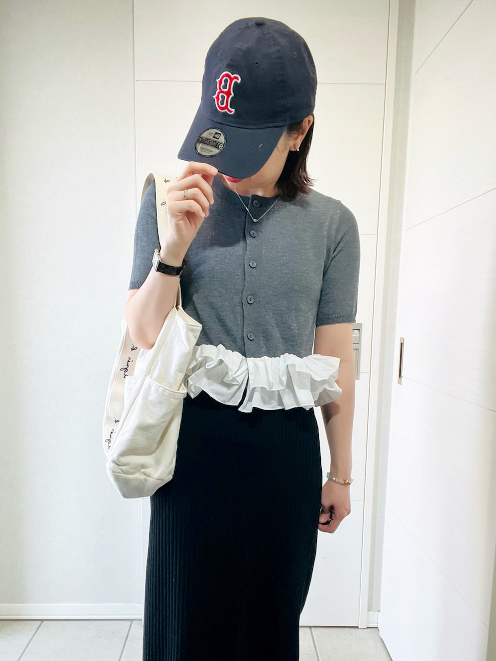 グレー系のカーディガン/ボレロ、ブラック系のスカート、グレー系のスニーカーを着用したレディースの春コーディネートの2枚目の写真