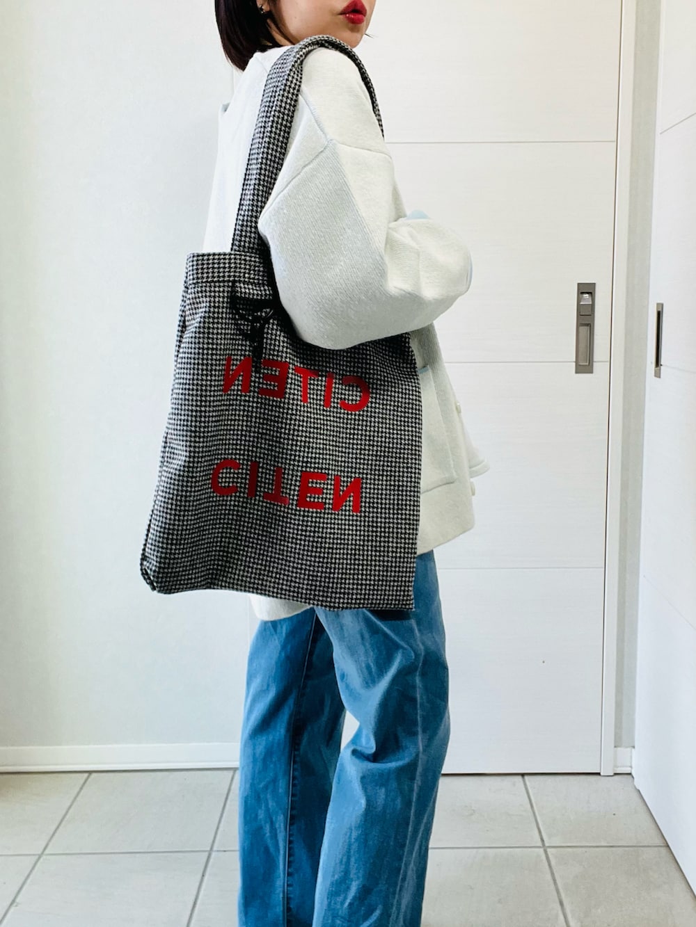 ホワイト系のカーディガン/ボレロ、ブルー系のデニムパンツ、ブラック系のトートバッグを着用したレディースの春コーディネートの3枚目の写真