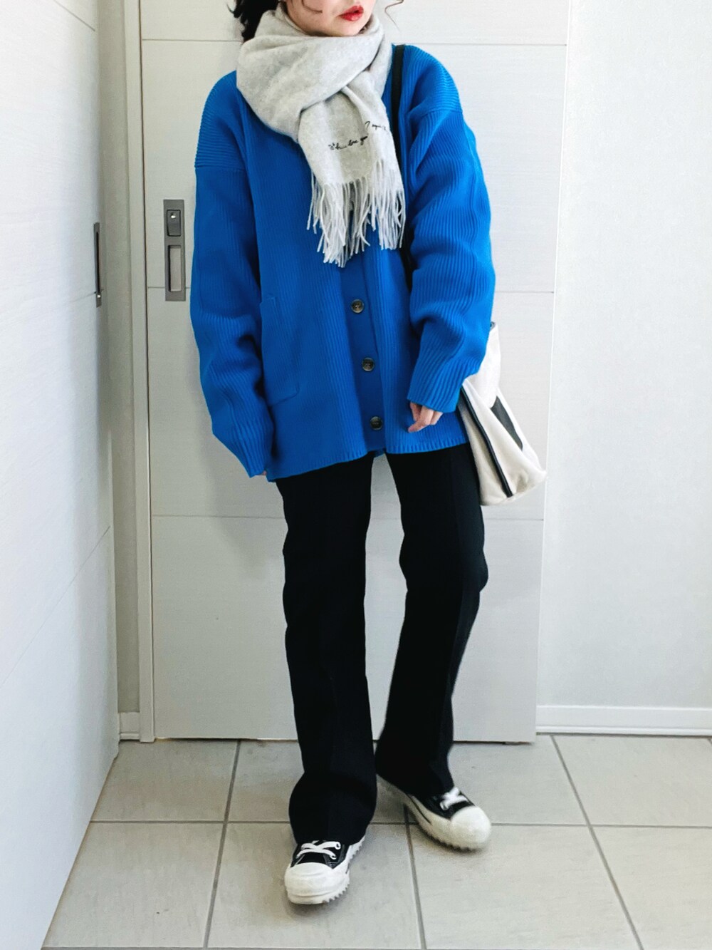 ブルー系のカーディガン/ボレロ、ホワイト系のTシャツ/カットソー、ブラック系のスラックスを着用したレディースの春コーディネートの2枚目の写真