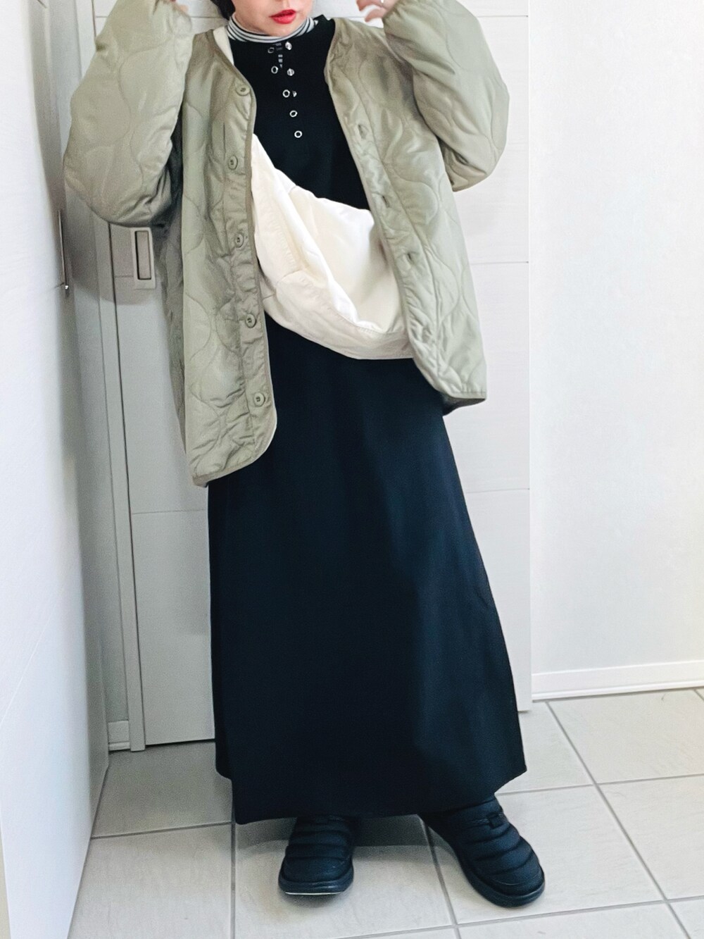 ブラック系のワンピース、ホワイト系のショルダーバッグ、グリーン系のノーカラージャケットを着用したレディースの冬コーディネートの4枚目の写真