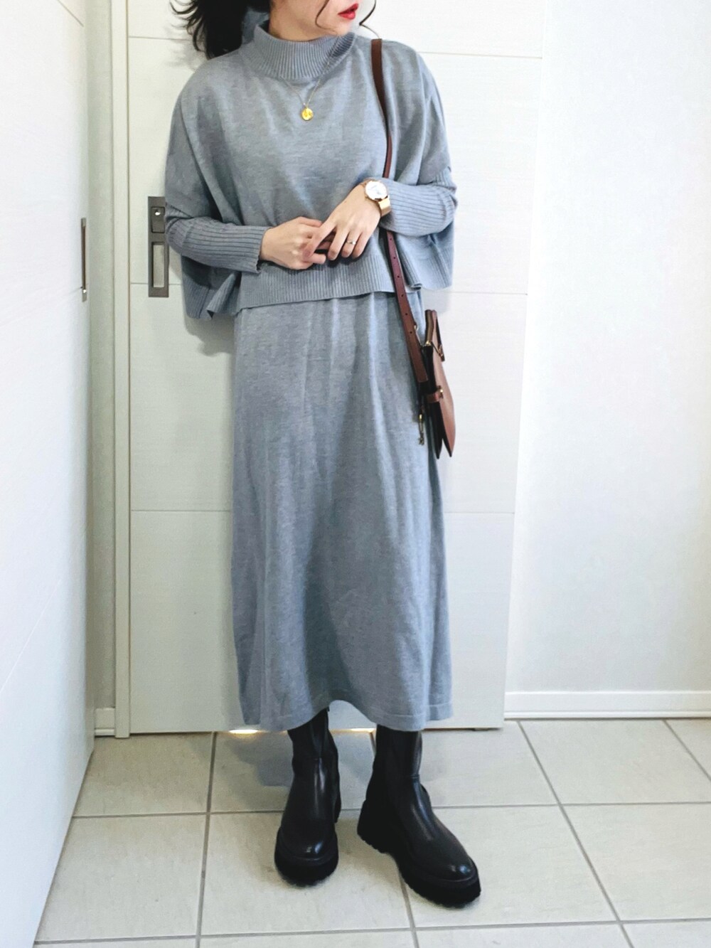 グレー系のワンピース、ピンク系のノーカラーコート、ブラウン系のブーツを着用したレディースの冬コーディネートの3枚目の写真