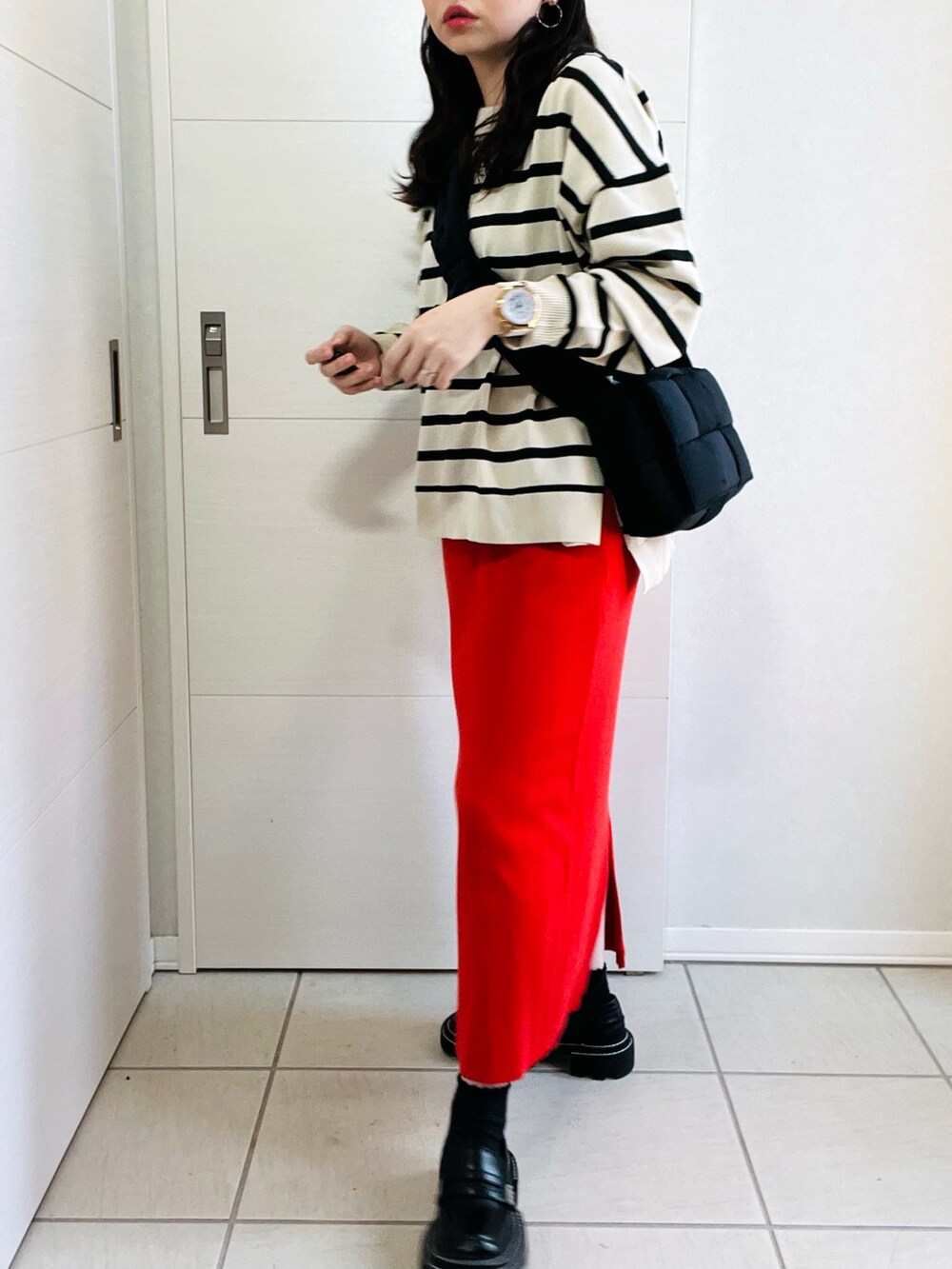 ホワイト系のニット/セーター、オレンジ系のスカート、ブラック系のローファーを着用したレディースの秋コーディネートの4枚目の写真