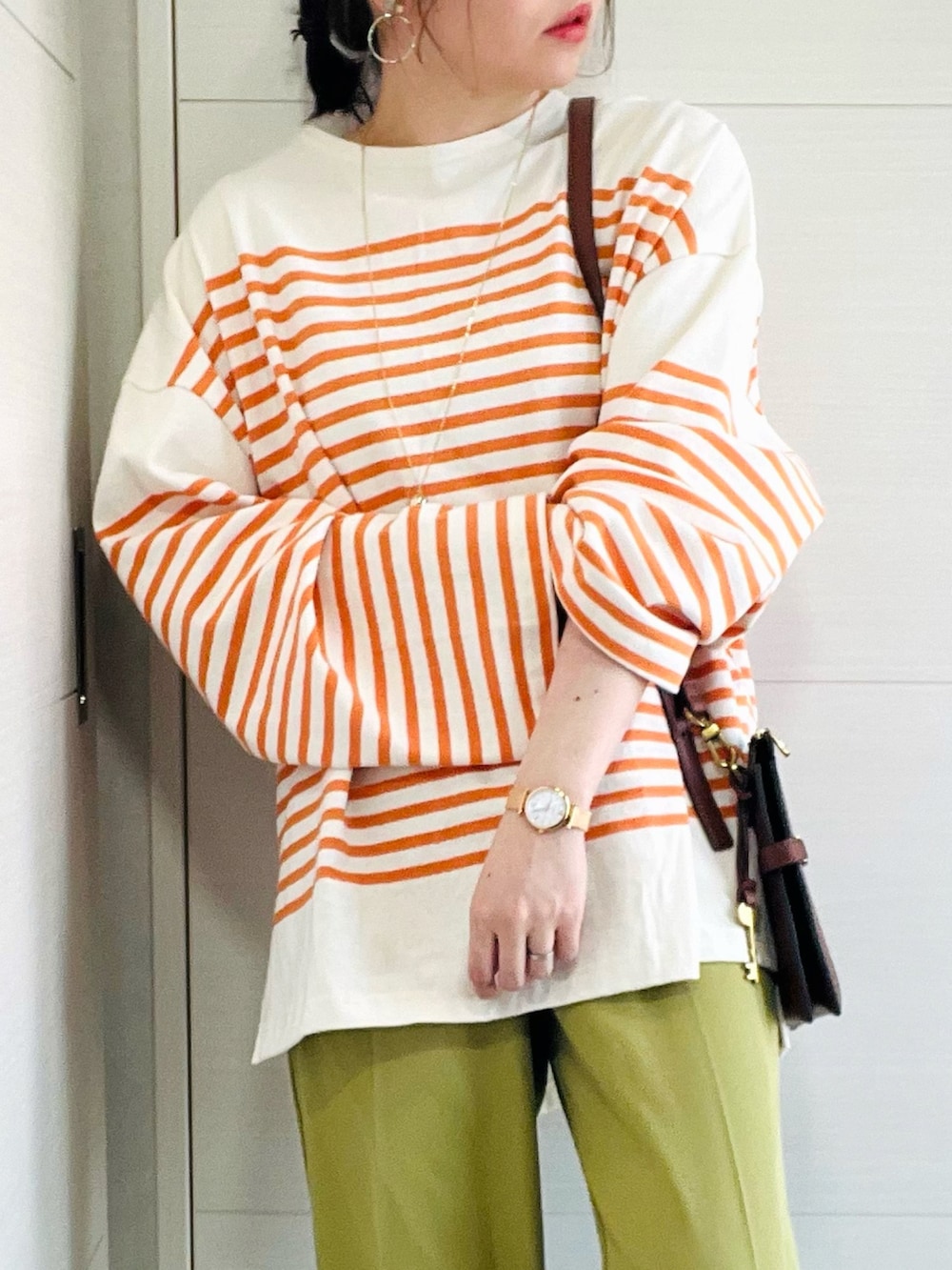 オレンジ系のTシャツ/カットソー、グリーン系のスラックス、ホワイト系のスニーカーを着用したレディースの春コーディネートの3枚目の写真