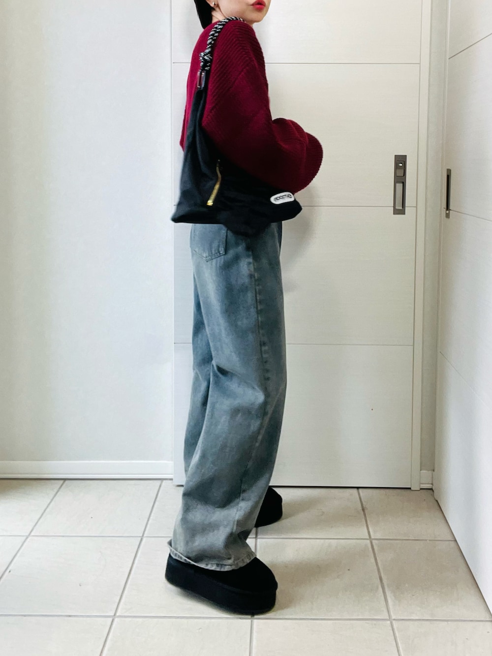 レッド系のカーディガン/ボレロ、ブラック系のブーツ、ブルー系のデニムパンツを着用したレディースの秋コーディネートの5枚目の写真