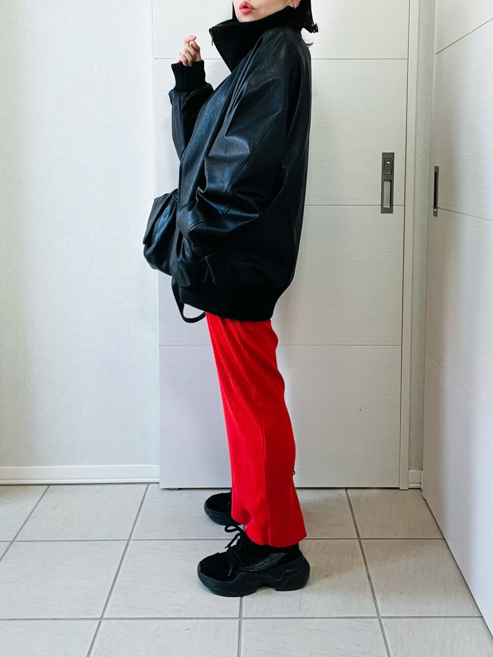 ブラック系のブルゾン、ホワイト系のニット/セーター、オレンジ系のスカートを着用したレディースの冬コーディネートの4枚目の写真