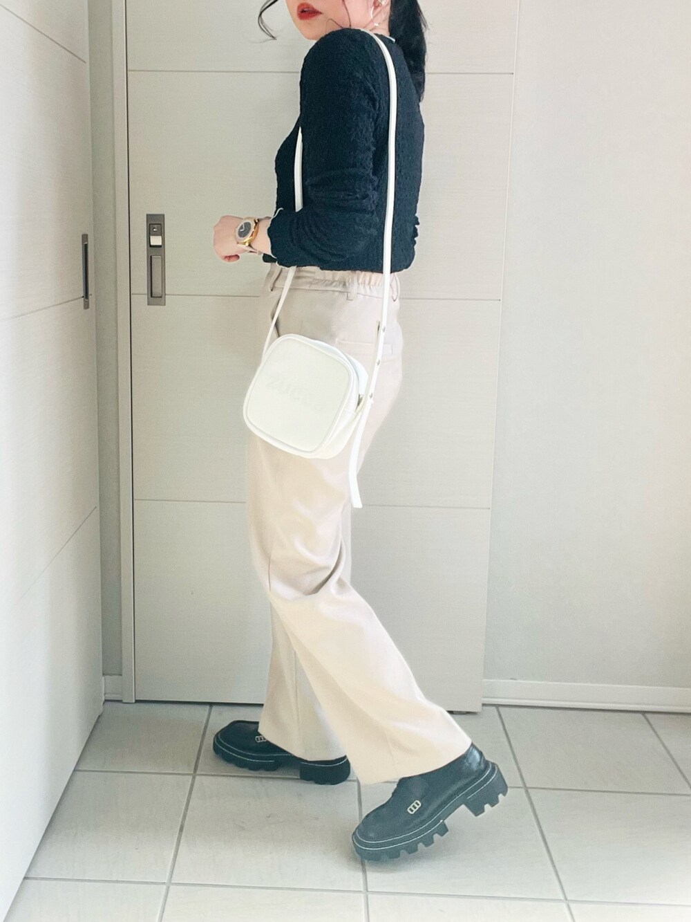 ブラック系のTシャツ/カットソー、ホワイト系のスラックス、ブラック系のローファーを着用したレディースの春コーディネートの4枚目の写真