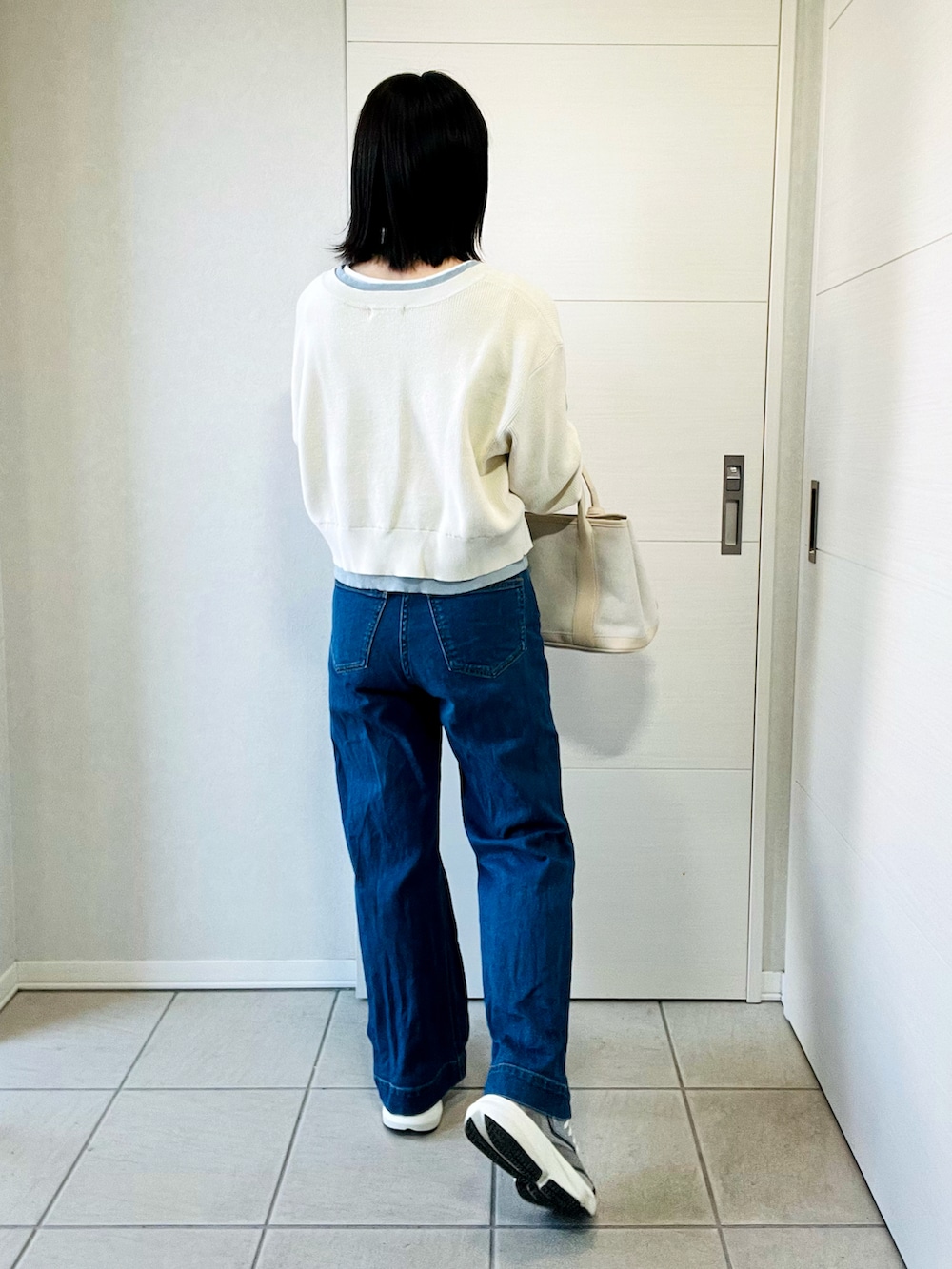 ホワイト系のカーディガン/ボレロ、グレー系のスニーカー、ブルー系のデニムパンツを着用したレディースの春コーディネートの3枚目の写真