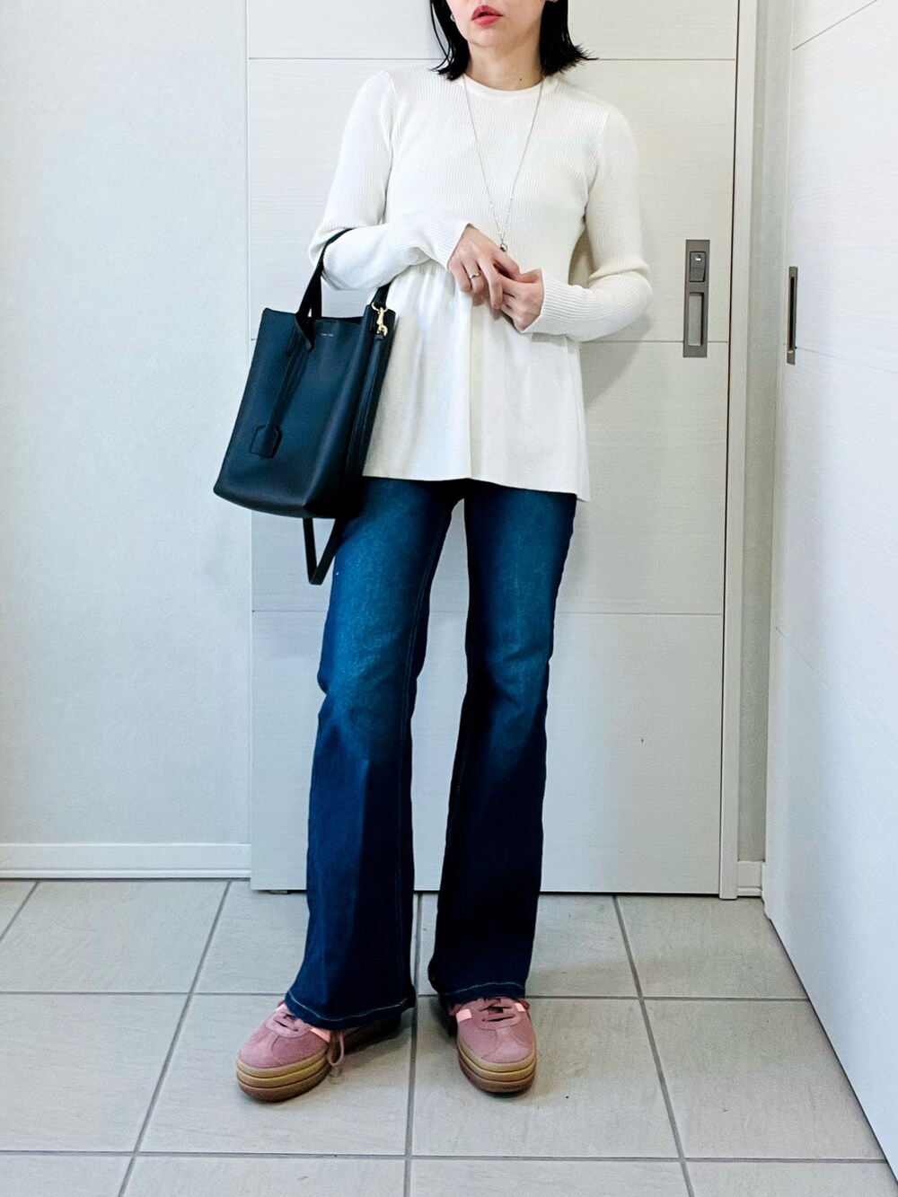ホワイト系のニット/セーター、ブルー系のデニムパンツ、レッド系のスニーカーを着用したレディースの春コーディネートの4枚目の写真