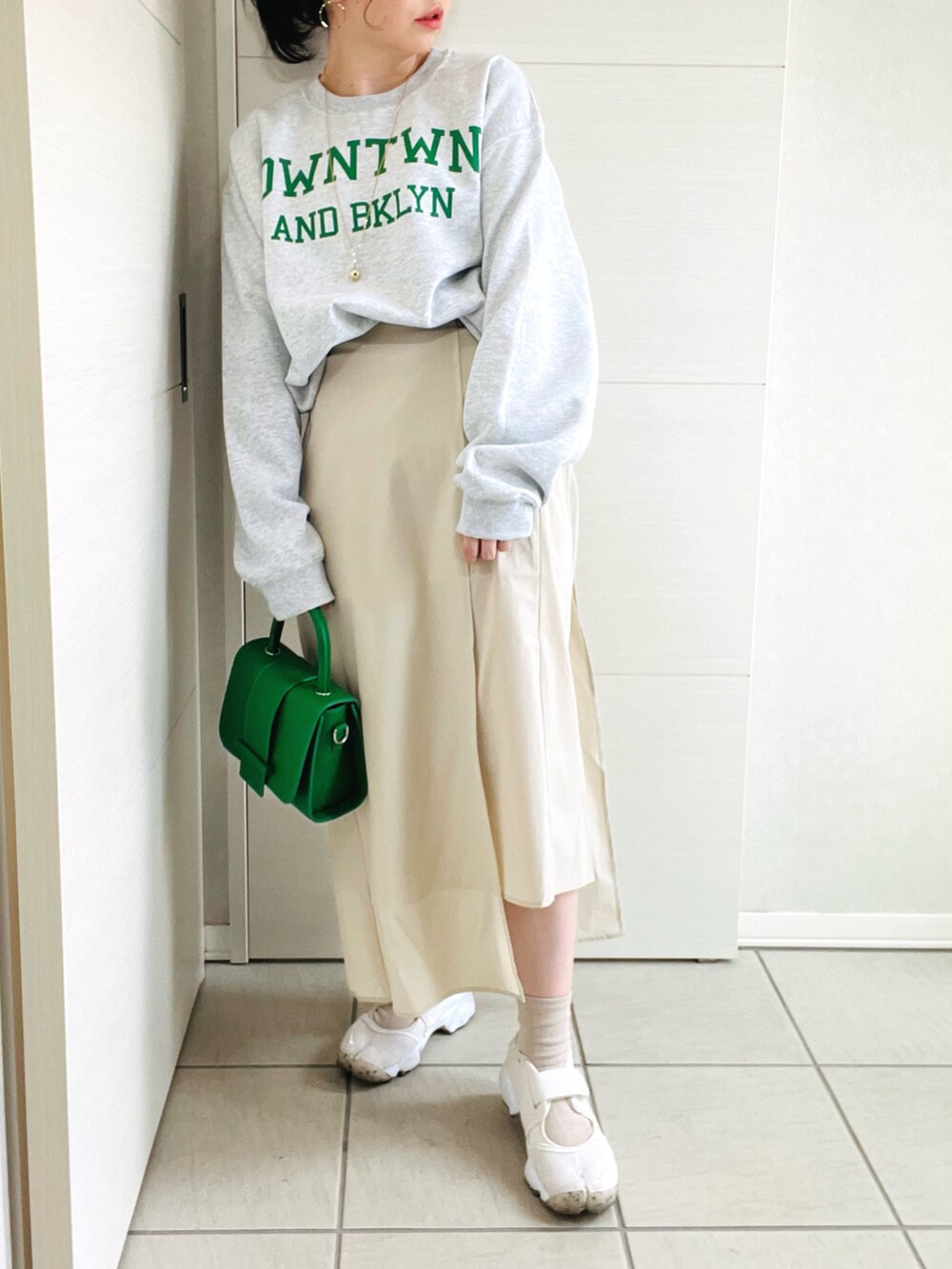 グレー系のスウェット、ベージュ系のスカート、ホワイト系のスニーカーを着用したレディースの春コーディネートの2枚目の写真